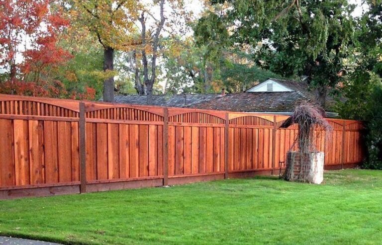 Redwood fence with arches in font of turf lawn