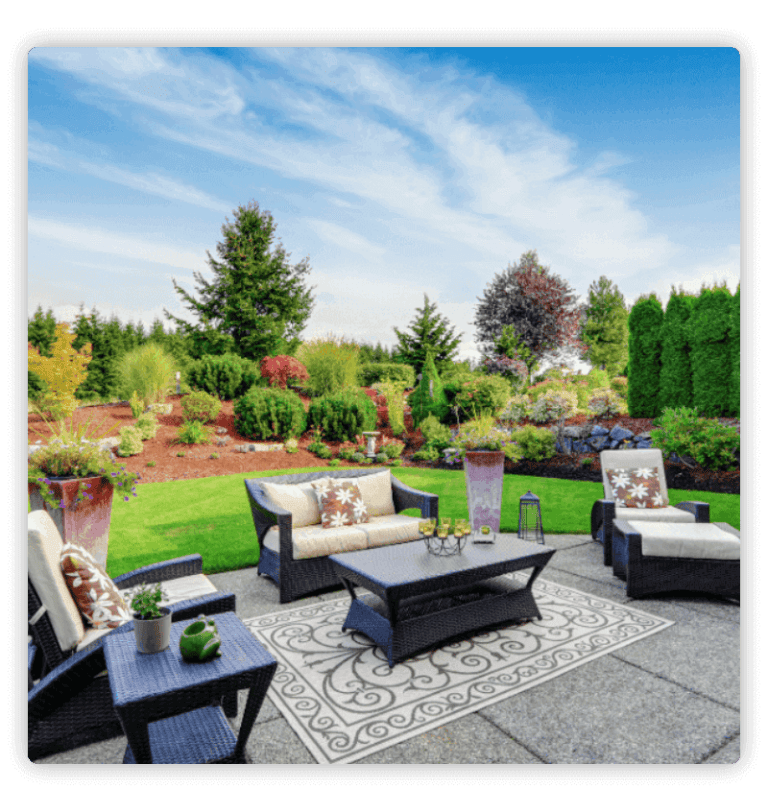 Backyard patio with sofas and a table; large colored trees in the background
