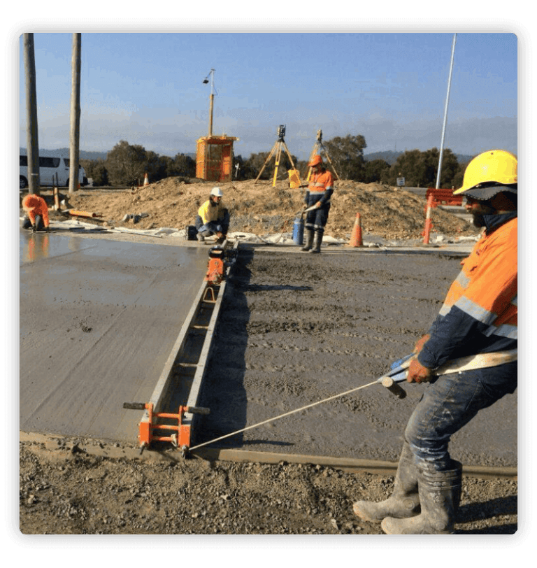 Men leveling wet cement wearing orange vests and helmets